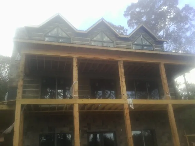 Dormers and porch framing on a large log home under construction — Roof Coating work by our crew in Donnelly